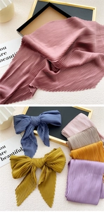 Detailed view of pleated silk scarves in various vibrant colors with bow-knot styling