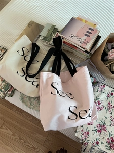 Detail of minimalist cream and pink canvas tote bags with See Sea print in a cozy setting