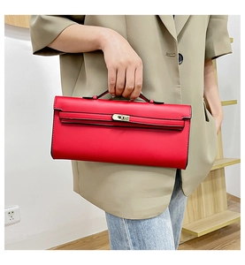 Close-up of a red leather handbag with gold twist lock held by a model in a beige blazer