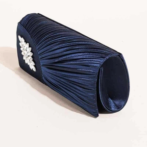 Detail der plissierten marineblauen Satin-Clutch mit eleganter Kristallblume für den Abend