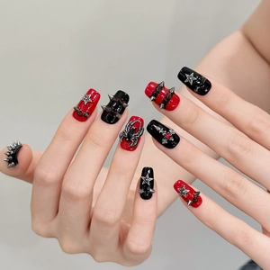Punk style press-on nails with red and black design featuring silver stars and spider charms