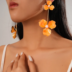 Model wearing orange bohemian double flower earrings with central pearl details
