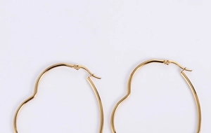 Close-up detail of the secure clasp and polished curve on gold heart hoop earrings