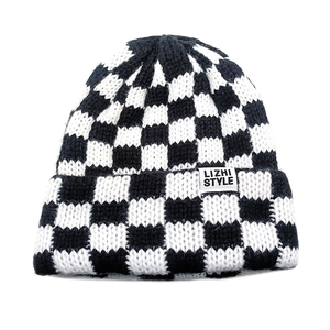 Close-up of checkerboard knit beanie texture with a minimalist woven brand label detail
