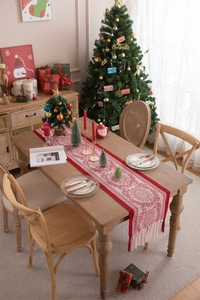 Festive red table runner with white patterns and tassels on a Christmas wooden table