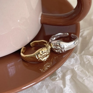 Close-up of hammered irregular silver and gold rings on ceramic tableware