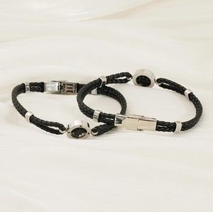 Detail of black braided leather bracelet with silver compass magnetic stainless steel clasp