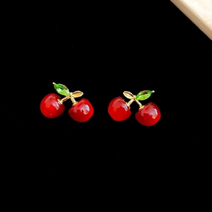 Detail of red resin cherry earrings with green crystal leaves and golden stems