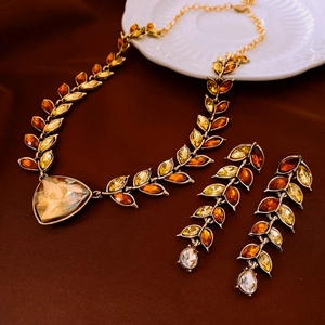 Detail of vintage gold-tone necklace and earrings with amber gemstones on ceramic plate