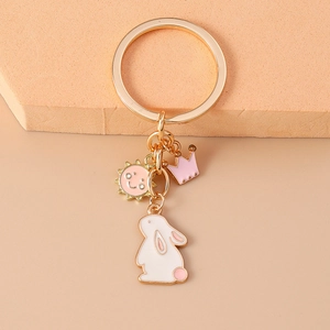 Detail of golden keychain with pink crown, smiling sun and white rabbit charms