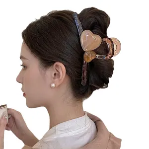 Elegant large amber hair claw clip with pink heart motifs worn by model on back of head