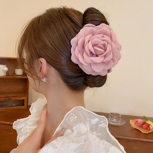 Detail of a pink fabric rose hair claw clip worn by a model in a cozy INS style setting