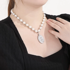 Gros plan du pendentif Saint-Christophe sur un collier de perles blanches pour femme