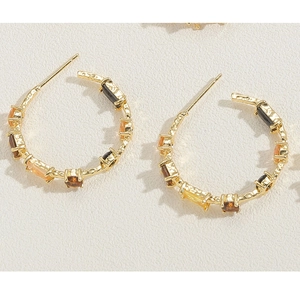 Detail of 14K gold C-shaped earrings with hammered texture and multi-colored zircons