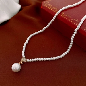 Close-up of pearl necklace with gold pave crystal connector on red velvet background