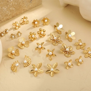 Detailed view of assorted gold flower earrings with pearl centers on stone texture