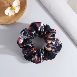 Detailed view of festive black satin scrunchie with gift box and bow holiday patterns