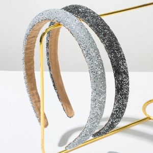 Sparkly sequin padded headbands in silver and charcoal on a gold metal stand