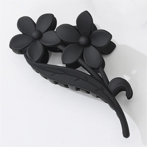 Macro detail of large matte black floral hair claw clip with dual flower and leaf design