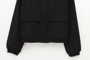 Detailansicht der schwarzen Jacke mit Pattentaschen, Druckknöpfen und Rippbündchen