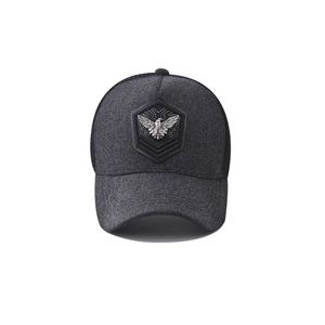 Detalle de la gorra trucker gris con parche de cuero negro y emblema de águila de metal
