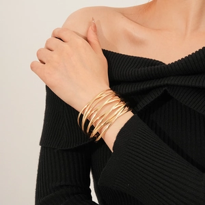 Close-up of layered crisscross gold cuff bracelet worn by model on black knit top