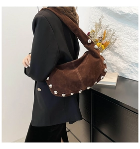 Dettaglio borsa a tracolla in pelle scamosciata marrone con borchie argentate e texture morbida
