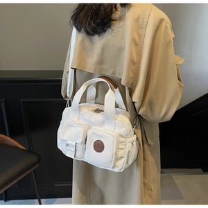 Detailansicht einer weißen Nylontasche, getragen von einem Modell im beigen Trenchcoat