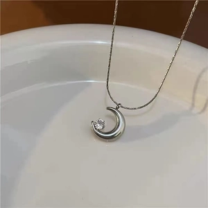 Detailed view of silver crescent moon pendant with inlaid zircon on fine chain