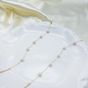 Elegant minimalist gold chain pearl necklace displayed on a white ceramic plate