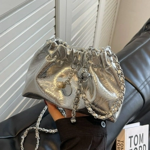 Silver pleated metallic cloud bag with chain strap and pearl charm held by hand