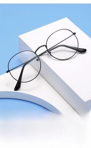 Detail view of vintage round black metal glasses frame on a white geometric prop