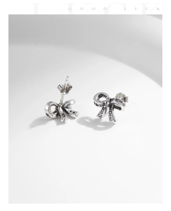 Macro shot of s925 silver bow stud earrings with vintage oxidized finish and pavé zircon