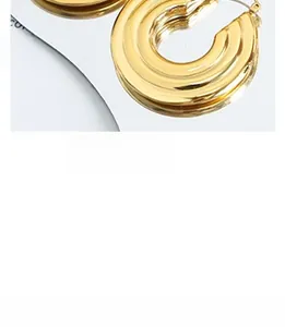 Macro shot of tiered golden hoop earrings with polished metal finish and industrial style