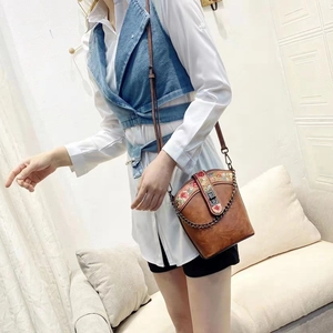 Brown crossbody bag featuring ethnic embroidery details worn by model in a cozy indoor setting