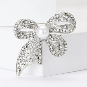 Detailed view of silver bow brooch with pearls, rhinestones and filigree craft