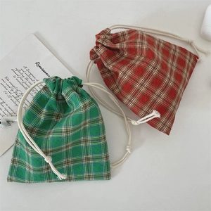 Detail of red and green plaid drawstring pouches with woven rope on a white background