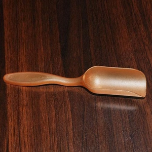 Rose gold plastic small measuring spoon for tea and powder on brown wood table