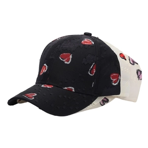 Detail of baseball cap showing red heart patterns on black fabric with cream mesh back