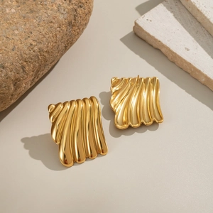 Détails de boucles d'oreilles géométriques dorées avec texture plissée sur pierre