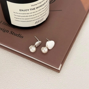 925 silver brushed geometric stud earrings with white pearls on a vintage book edge
