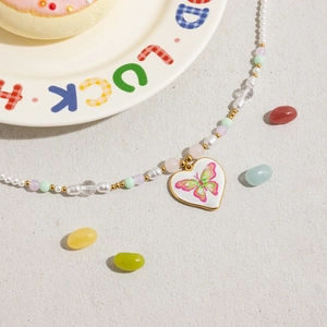Détail du collier de perles avec pendentif cœur papillon et perles macaron colorées