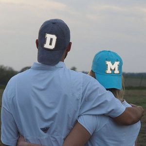Outdoor shot of washed cotton baseball caps with large chenille letter patches D and M