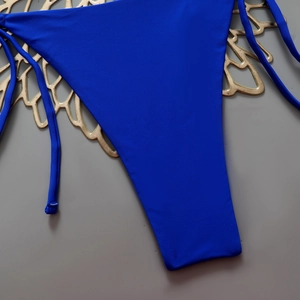 Close-up of royal blue bikini bottoms with side ties on a gold decorative tray