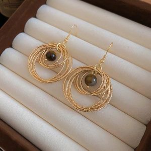 Detailed view of gold multi-layered hoop earrings with round dark tiger eye stone beads