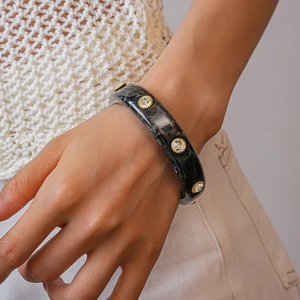Macro detail of acrylic marble bangle with inlaid rhinestones on a model's wrist