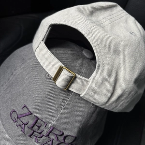 Close-up of adjustable bronze metal buckle and stitching on cotton baseball caps