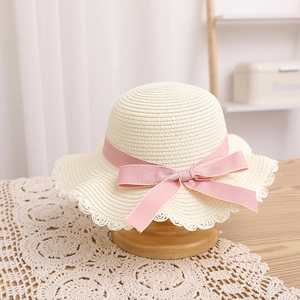 Détail du chapeau de paille pour enfant avec bordure en dentelle et nœud en satin rose