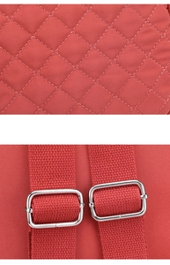 Detail of red quilted nylon fabric and silver metal buckle on a shoulder backpack