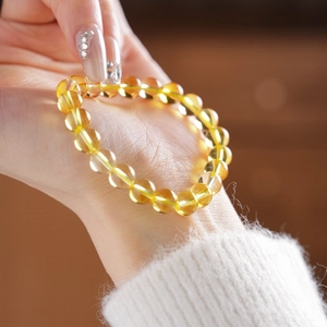 Macro detail of yellow citrine beaded bracelet on a woman wrist with cozy light